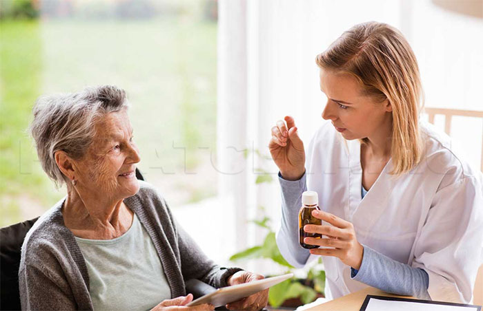 Геронтолог дает лекарства пожилой женщине - фото